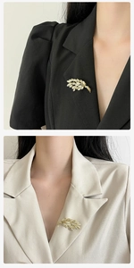 Détail de la broche épi de blé dorée épinglée sur des revers de blazer noir et beige