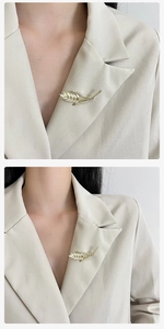 Macro detail van luxe gouden tarwe broche met opaalstenen op een beige pak revers