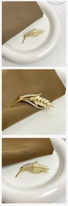 Detail van gouden tarwebroche met opalen kattenoogstenen en fonkelende zirkonen
