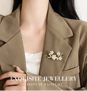 Close-up of pearl flower brooch with green leaves on a brown suit lapel