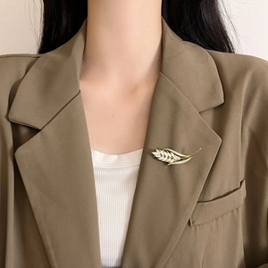 Elegante korenaren broche met kattenoogsteen en goudlaag op een bruine colbert