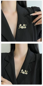 Detail view of flower brooch with pearls and green leaves on black suit lapel