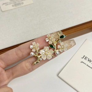 Elegant gold-plated flower brooch with white pearls, crystals, and green enamel leaves