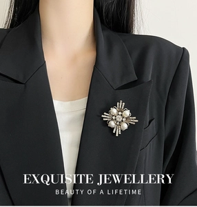 Detalle de broche de cruz retro con perlas y diamantes sobre un blazer negro formal