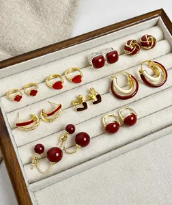 Gros plan de boucles d'oreilles perles rouges et dorées dans un plateau à bijoux beige