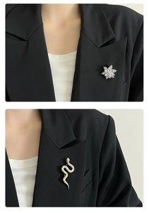 Détail de la broche flocon de neige argentée et de l'épingle serpent dorée sur un blazer