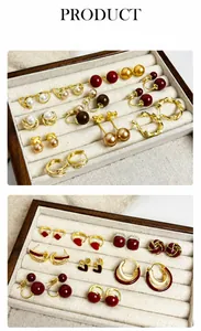Détail de boucles d'oreilles perles et clous dorés dans un coffret à bijoux en bois