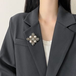 Broche vintage de estrella dorada con cristal y perlas en solapa de traje gris