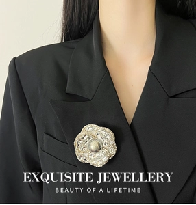 Détail d'une broche camélia de luxe avec strass et perle sur un blazer noir élégant