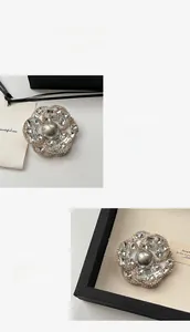 Détails de la broche camélia avec zircons scintillants et perle grise au centre
