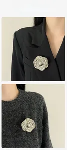 Détail de la broche camélia de luxe avec strass et perle grise sur un vêtement