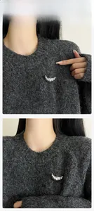 Detail of silver croissant brooch with brushed texture pinned on a dark grey knit sweater