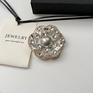 Élégante broche camélia avec perle grise et cristaux sur fond minimaliste blanc