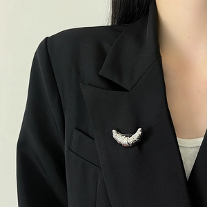 Silver croissant brooch with pleated texture pinned on black suit lapel for women