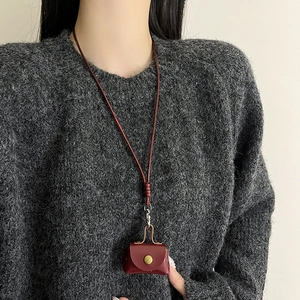 Collier pendentif mini sac en cuir rouge foncé sur pull en tricot gris femme