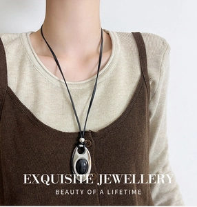 Macro detail of oval black gemstone pendant on long leather cord for women