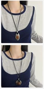 Detail of oval amber resin pendant on black leather cord necklace for women