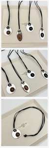 Detail of oval and round pendants on black cord necklaces with brown gemstones