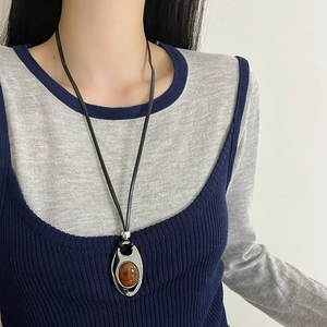 Oval amber stone pendant necklace with black leather cord and silver metallic frame