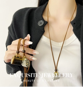 Detail of tiger eye stone pendant in handbag shape with golden handle and brown leather cord