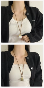 Detail of stone bag pendant necklace with gold handle and brown leather cord on a model