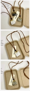 Detail of tiger eye and marble bag-shaped pendants on brown suede cords in a tray