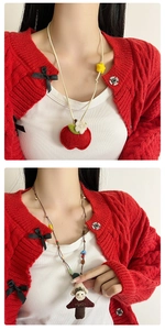 Detail van handgemaakte vilten appel en stoffen pop hanger ketting gedragen door model