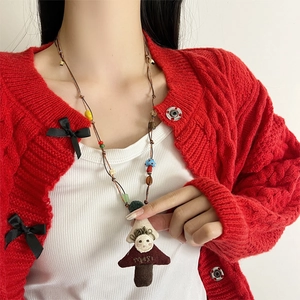 Kleurrijke stoffen pop hanger ketting op rode trui voor een schattige handgemaakte look