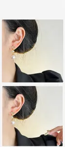 Detalle de pendientes de copo de nieve con circonita y perla blanca en acabado dorado