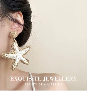 Close-up of woven raffia starfish earrings with natural fiber texture on a model