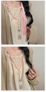 Dettaglio della collana di perline con nappe e anello in finta giada su lino beige