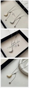 Close-up of gold and silver croissant pendant necklaces on minimalist display