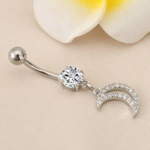 Makro-Detail des silbernen Mond-Bauchnabelpiercings mit Zirkonia auf Seidenstoff