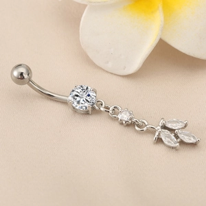 Macro detail of silver navel ring with round zircon and marquise leaf tassel pendant