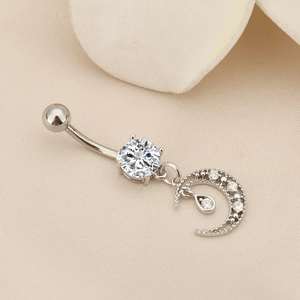 Macro shot of silver moon and teardrop zircon belly ring on soft fabric