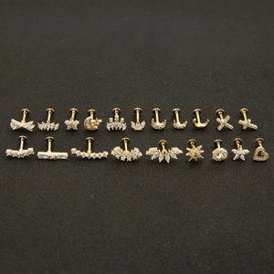 Golden cartilage studs set with moon and star zircon designs on dark background
