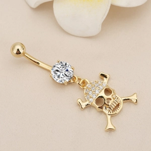 Detailed macro view of a skull belly button ring with 18K gold plating and micro-pave crystals