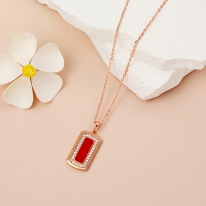 Detailansicht der Roségold-Halskette mit rotem rechteckigem Anhänger auf weißem Stein