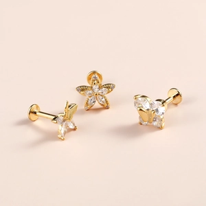 Macro detail of gold flower and butterfly labret studs with cubic zirconia inlays