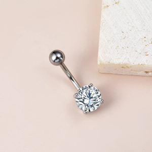 Détail d'un piercing de nombril en argent avec un grand zircon cubique rond brillant