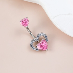 Macro shot of silver navel piercing featuring pink heart zircon and sparkling crystal halo