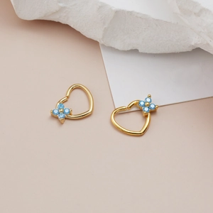Macro detail of heart shaped nose rings with blue zircon flower inlay in gold finish