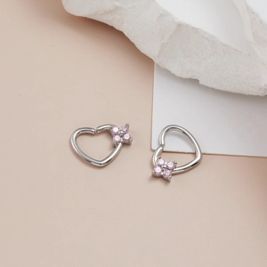 Macro view of silver heart piercing hoop with pink zircon flowers on pink stone