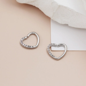 Detailed macro view of heart-shaped piercing studs with micro-pave cubic zirconia inlay