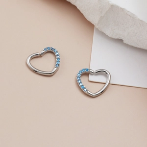 Macro shot of silver heart-shaped body jewelry with blue pavé-set cubic zirconia stones