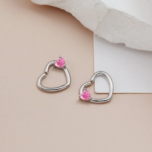 Orecchini a cuore in argento con zircone rosa su superficie di pietra minimalista