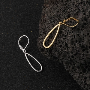 Boucles d'oreilles créoles ovales évidées en or et argent sur fond de pierre volcanique