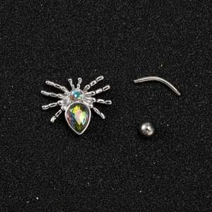 Vue macro d'un piercing nombril araignée argenté avec des strass irisés sur fond sombre