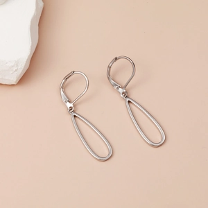 Boucles d'oreilles ovales argentées géométriques creuses sur fond minimaliste beige