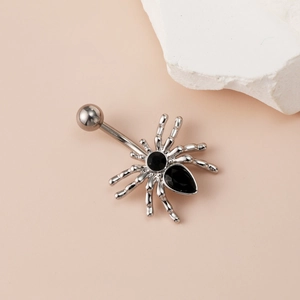 Silver spider belly button ring with black zircon stones on soft pink background